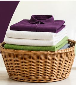 Wicker basket with folded plum, white, and green laundry
